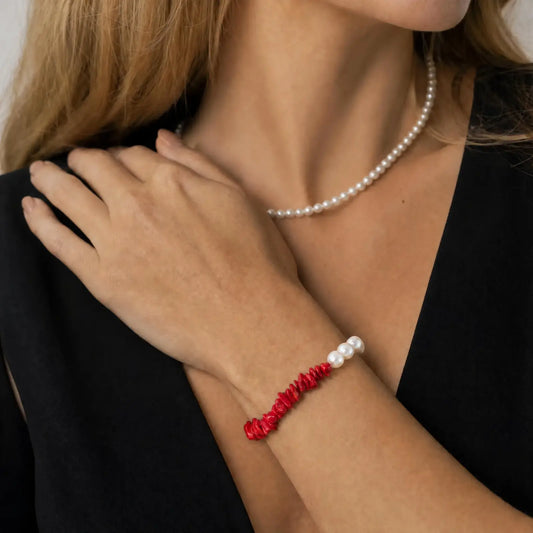 Styled wrist view of the Crimson Divide Pearl Bracelet with an asymmetric split of red stone chips and freshwater pearls