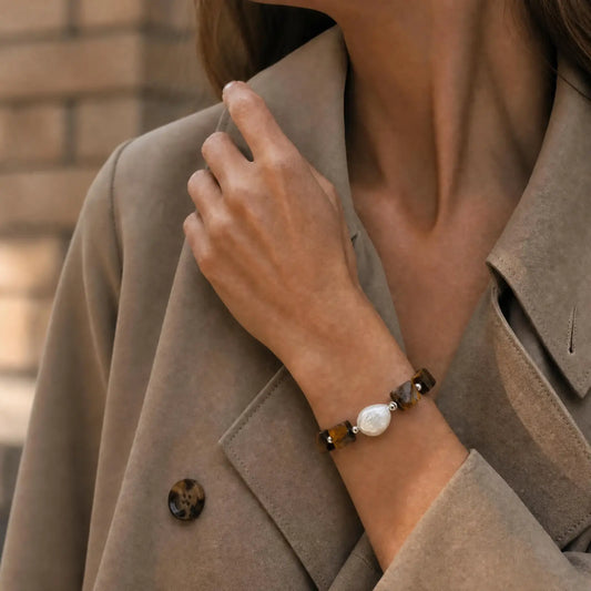 Woman wearing the Golden Block Tiger's Eye & Pearl Bracelet with faceted golden-brown tiger's eye blocks and a central baroque pearl