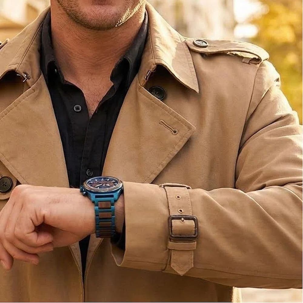 Man wearing a blue JOVYRA watch with brown wood bracelet inserts and a tan jacket