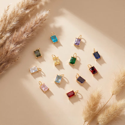 Twelve rectangular colored stone charms arranged on a warm neutral background