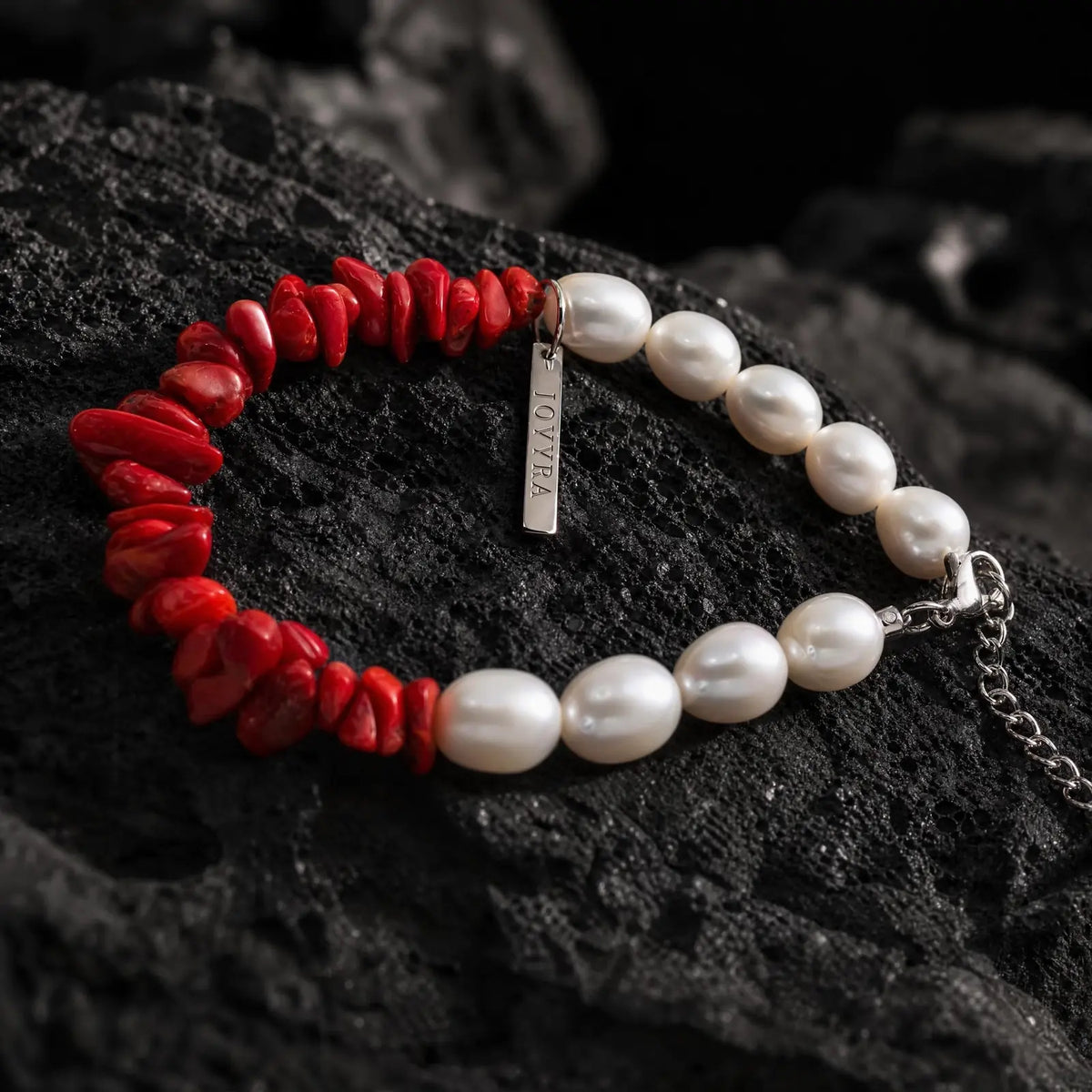 Angled view of the Crimson Divide Pearl Bracelet showing an asymmetric split of red stone chips and freshwater pearls