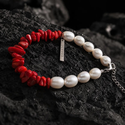 Angled view of the Crimson Divide Pearl Bracelet showing an asymmetric split of red stone chips and freshwater pearls