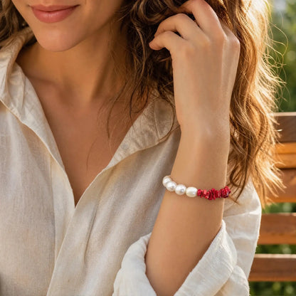 Close wrist view of the Crimson Divide Pearl Bracelet with an asymmetric split of red stone chips and freshwater pearls