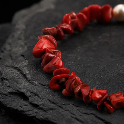 Detailed product view of the Crimson Divide Pearl Bracelet showing an asymmetric split of red stone chips and freshwater pearls
