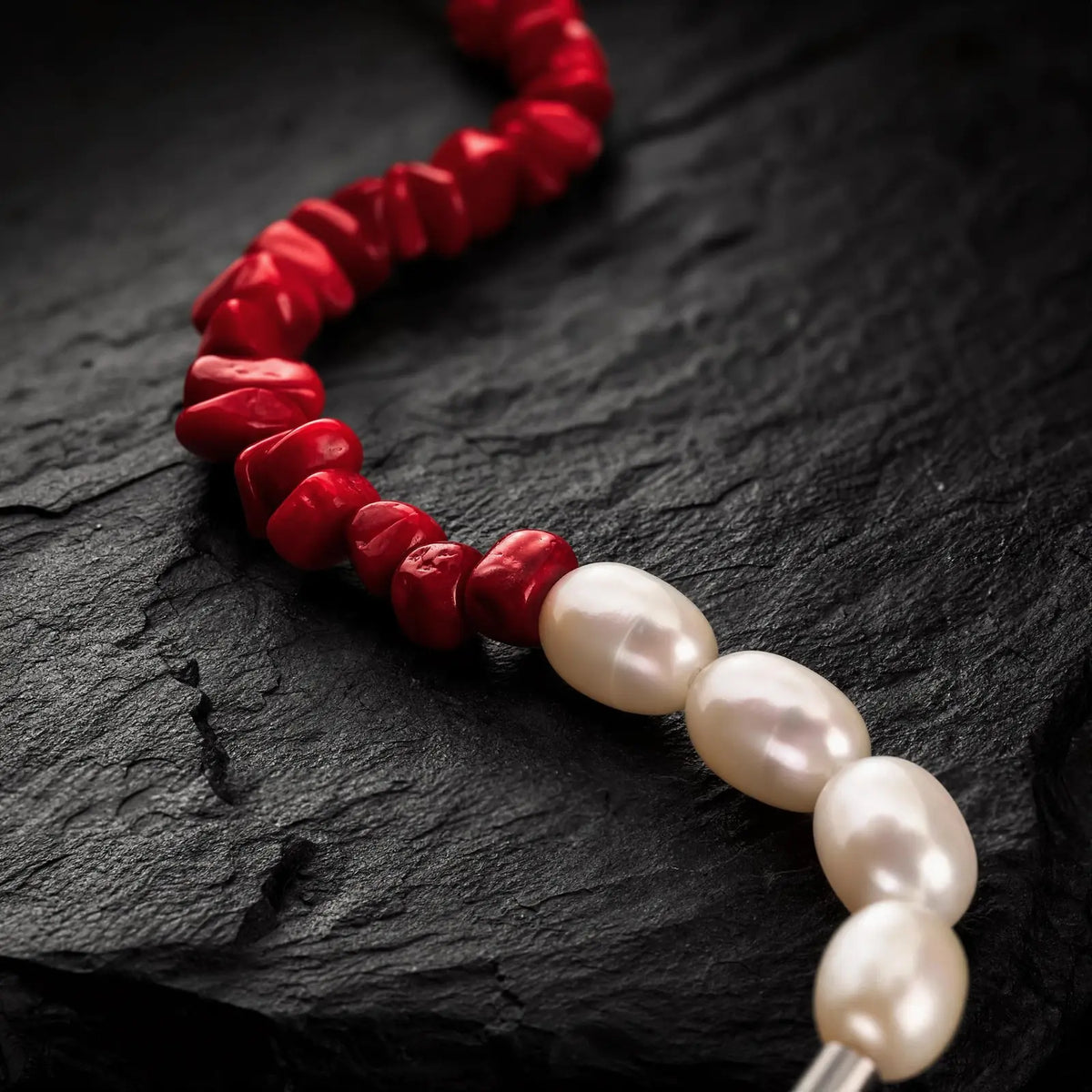 Flat-lay view of the Crimson Divide Pearl Bracelet showing an asymmetric split of red stone chips and freshwater pearls