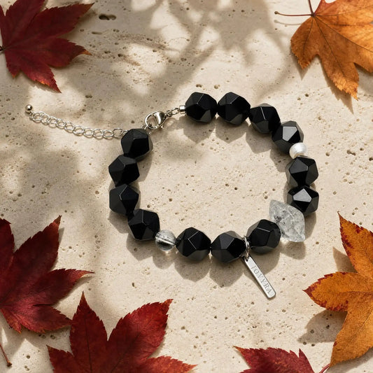 Flat-lay view of the Noir Facet Onyx & Pearl Bracelet showing faceted black onyx, translucent included quartz, and pearl accents