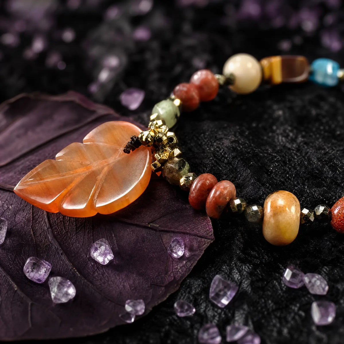 Carved amber leaf charm and mixed stone beadwork in close-up