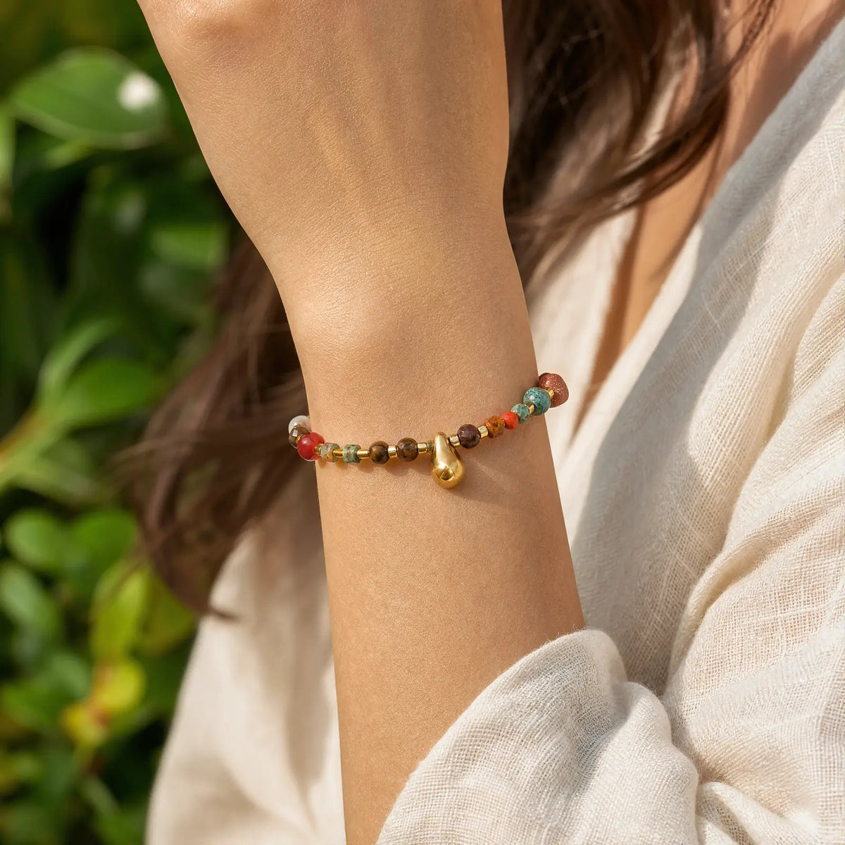 Tiger eye drop bracelet worn with a relaxed white sleeve