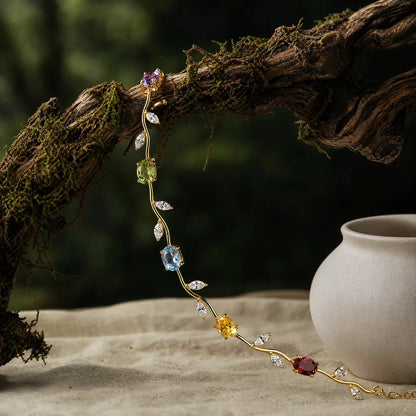 Multicolored vine bracelet draped over a mossy branch beside a ceramic vessel