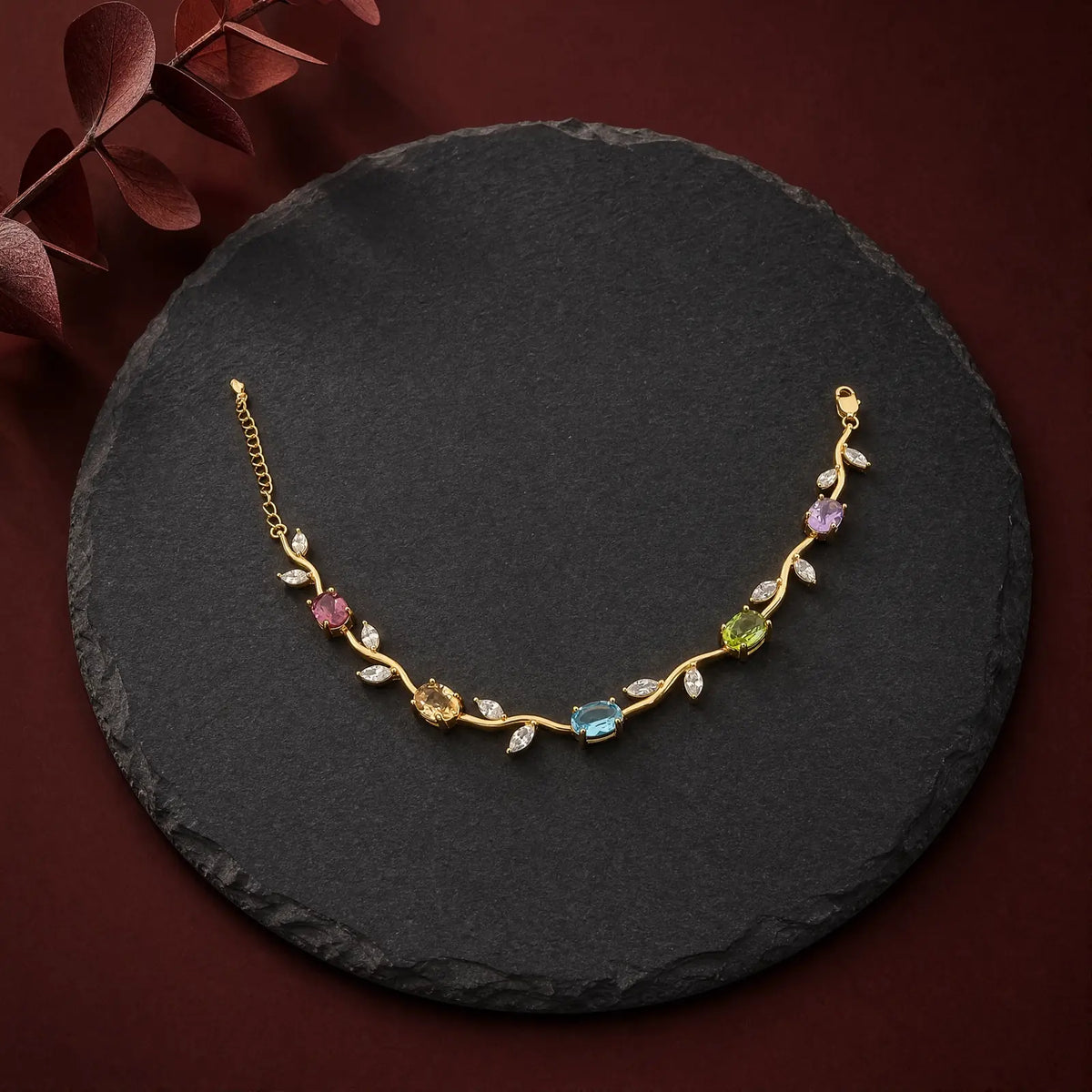 Natural multi-stone vine bracelet with gold-tone setting on dark slate