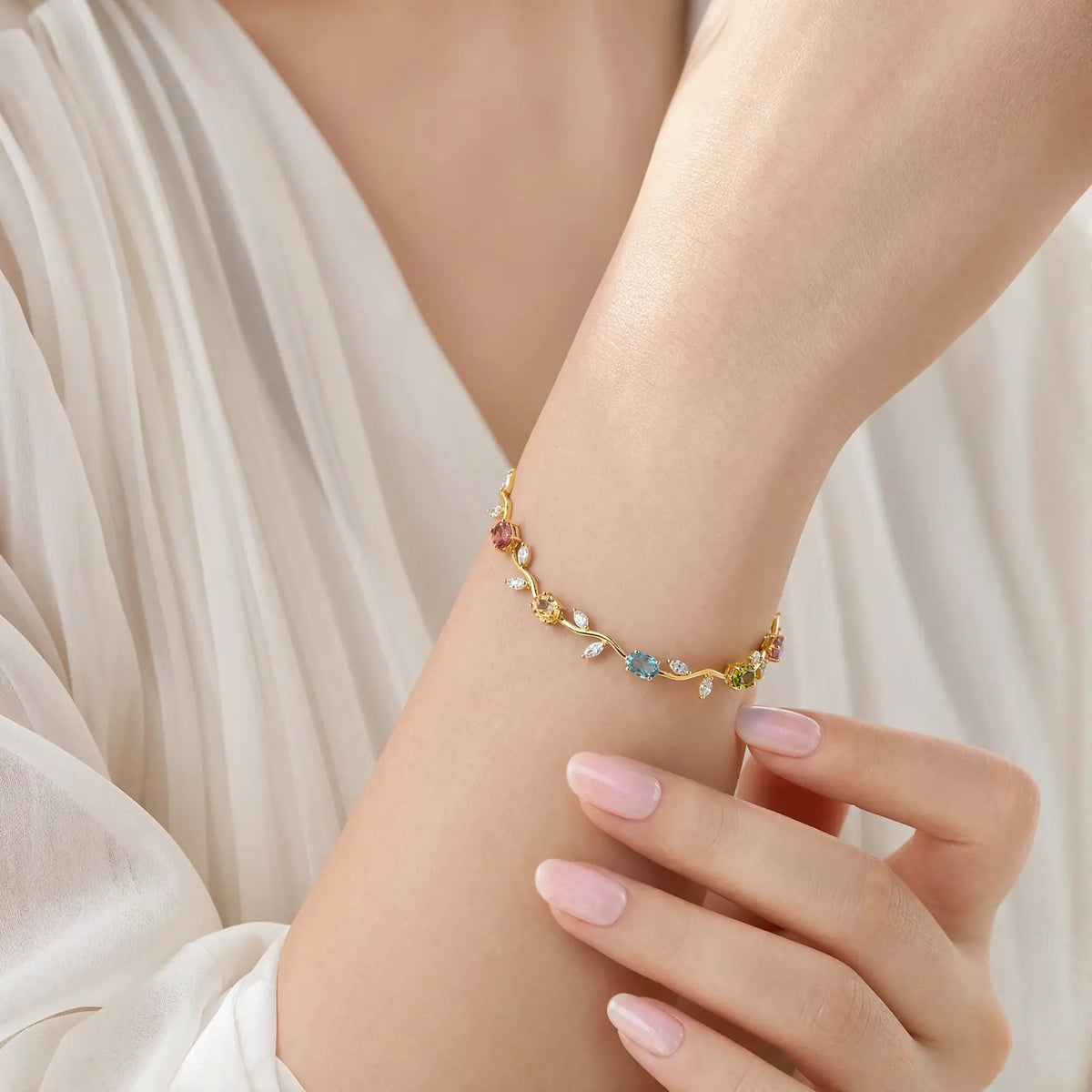 Multicolored vine bracelet worn on a woman's wrist against white fabric