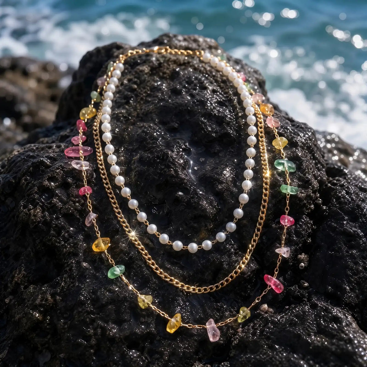 Pearlescent layered necklace and bracelet set on coastal rock