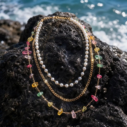 Pearlescent layered necklace and bracelet set on coastal rock