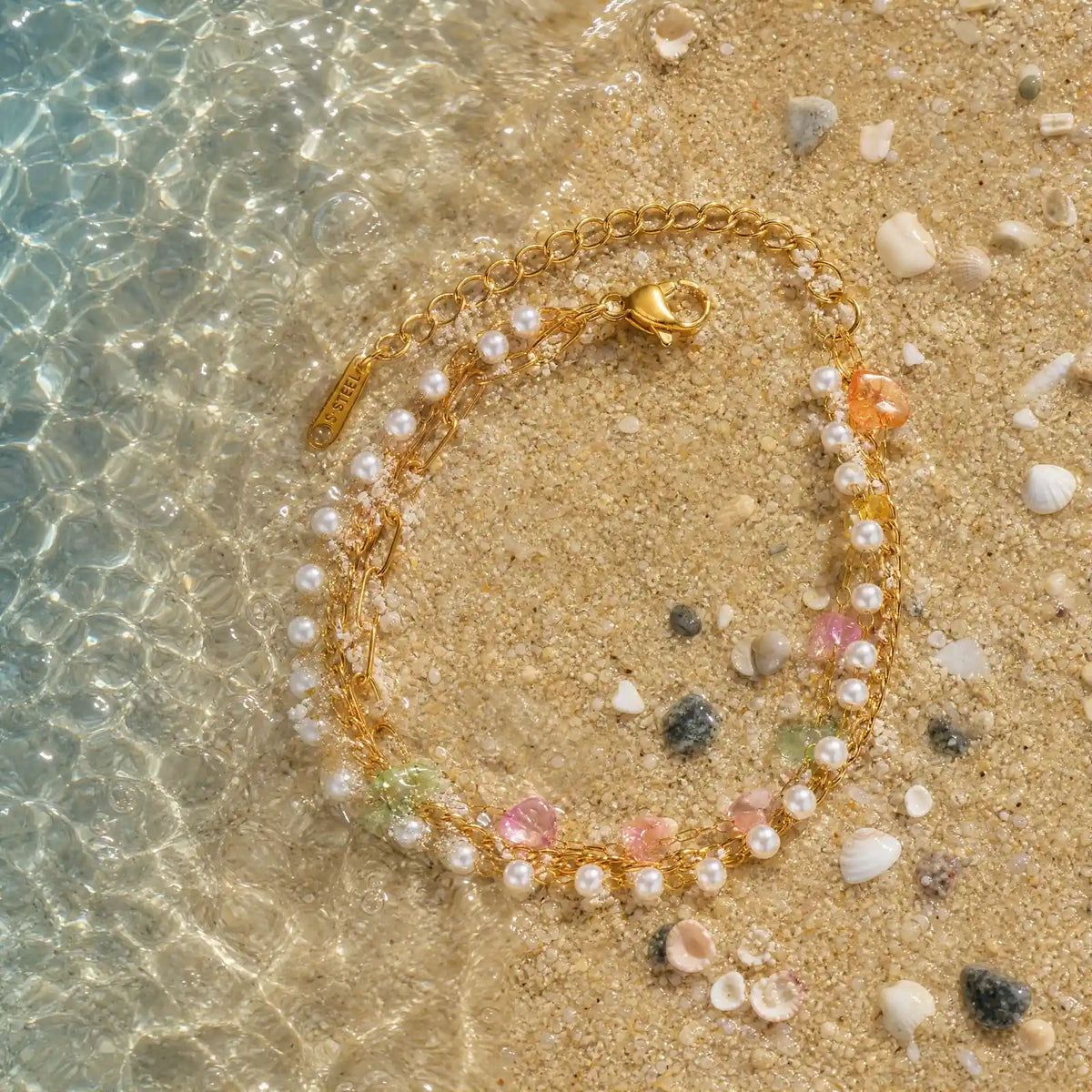 Pearlescent stainless steel strand arranged in shallow water on sand