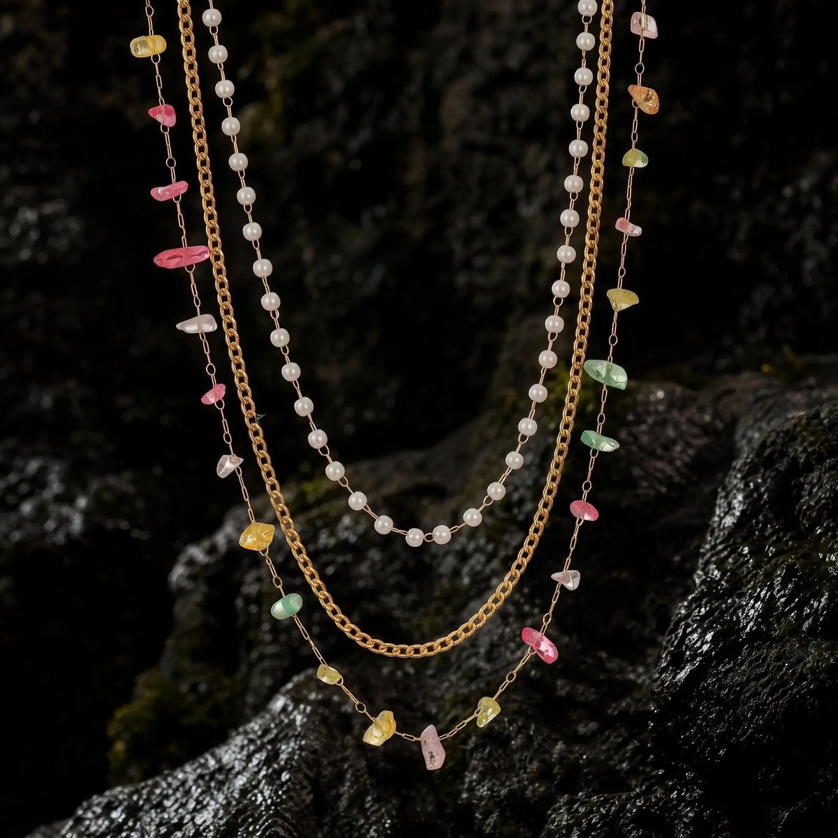 Pearlescent layered necklaces displayed on dark seaside rock