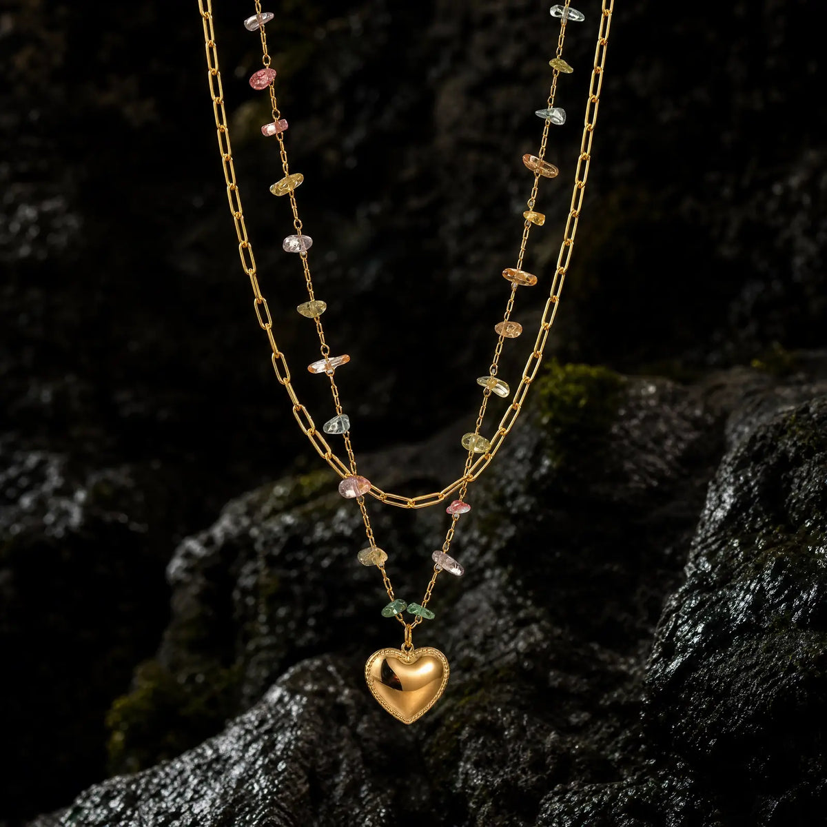 Heart pendant layered necklaces displayed on dark seaside rock
