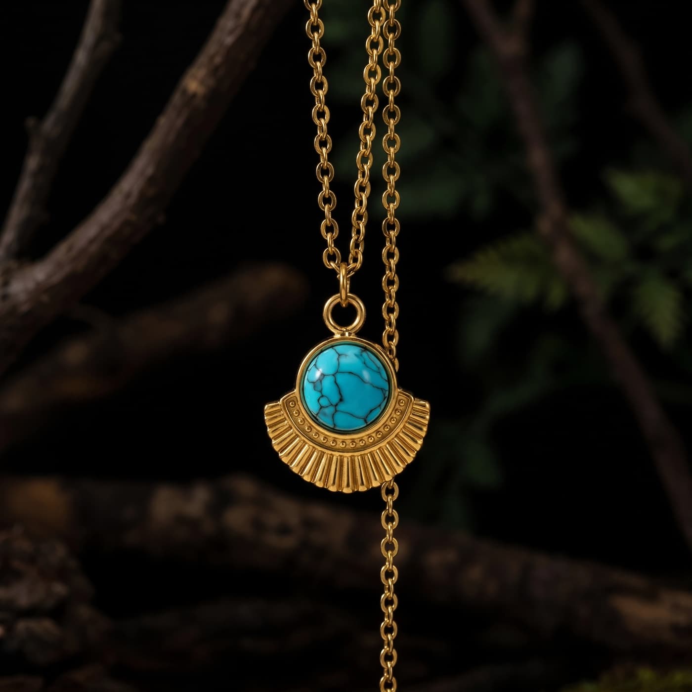 Oval natural turquoise pendant necklace with textured gold-tone frame on dark branches