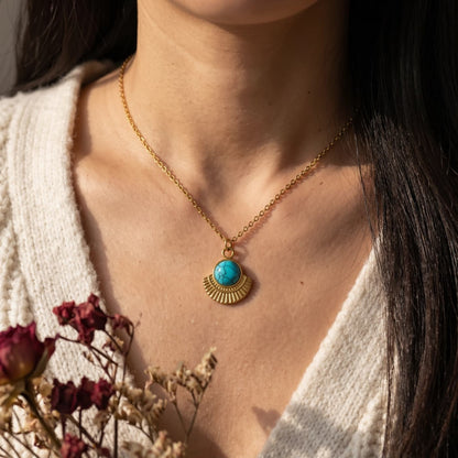 Round natural turquoise pendant necklace worn with a cream cardigan and flowers