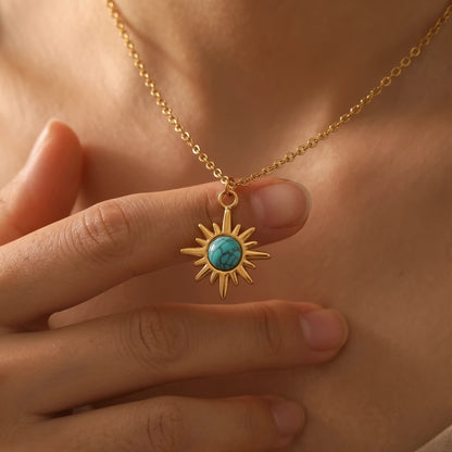 Hand holding a starburst natural turquoise pendant necklace at the neckline