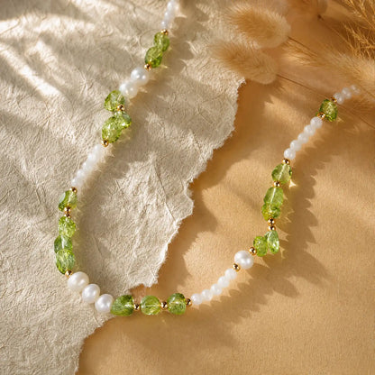 Peridot chip and pearl necklace arranged on warm cream fabric