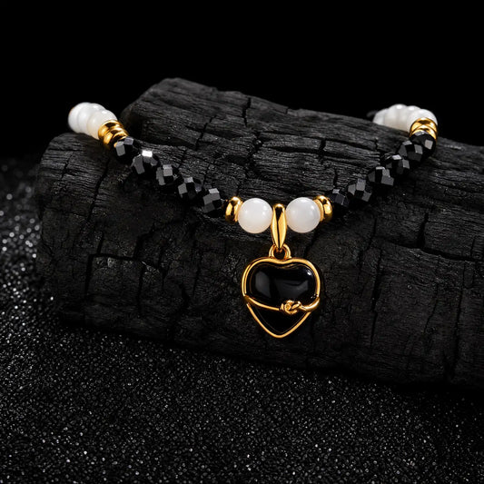 Detailed view of faceted black beads white shell accents and an onyx heart charm