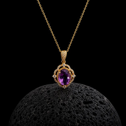 Oval amethyst pendant framed by a detailed gold-tone halo