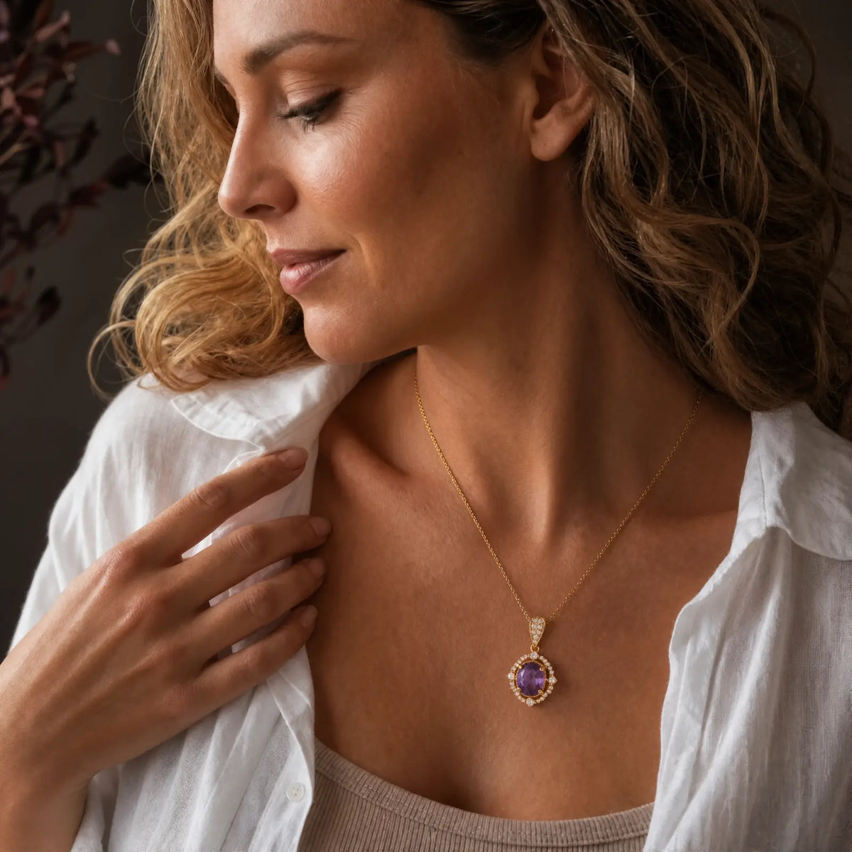 Woman wearing an amethyst oval halo pendant with a white shirt