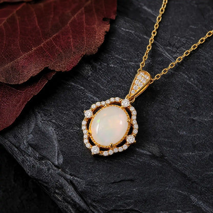 Oval opal pendant framed by a detailed gold-tone halo