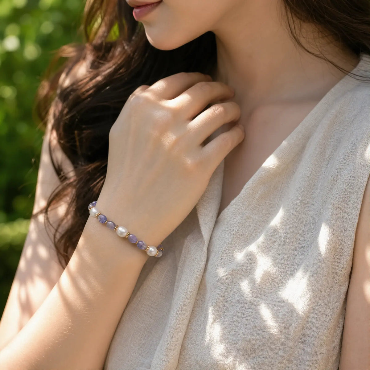 Woman wearing a blue-violet tanzanite and pearl bracelet