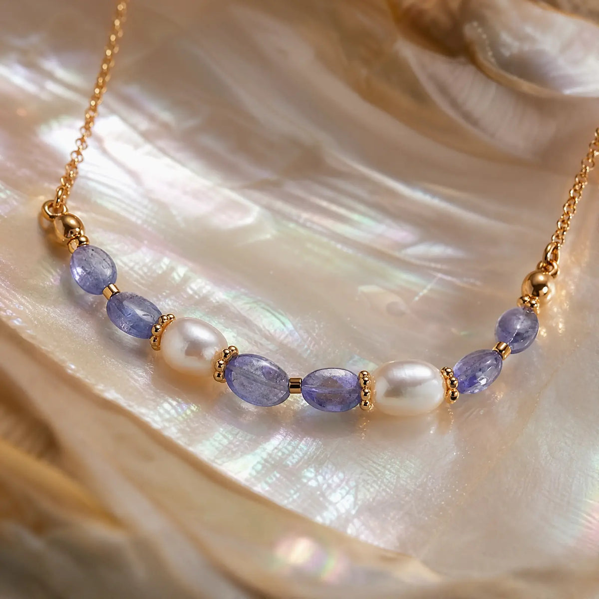 Tanzanite and pearl necklace displayed on an iridescent shell surface