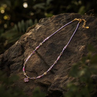 Lilac Clover beaded necklace on a dark mineral surface