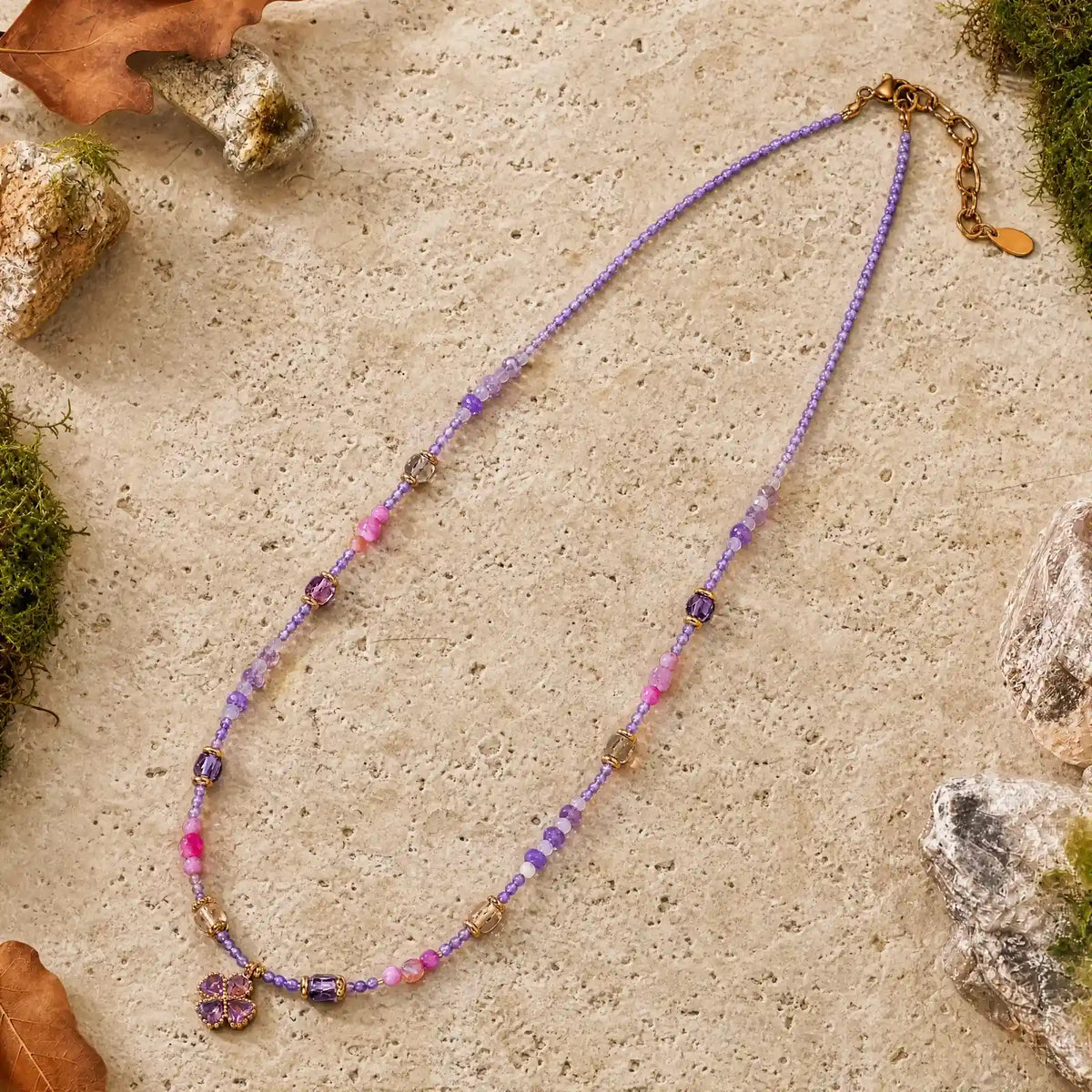 Lilac natural stone clover necklace arranged on a light mineral surface