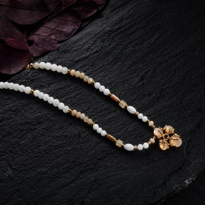 Close view of picture jasper shell beads and an opal cluster pendant on dark stone