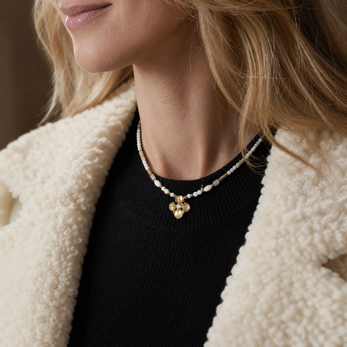 Woman wearing a pale beaded opal cluster necklace over a black top
