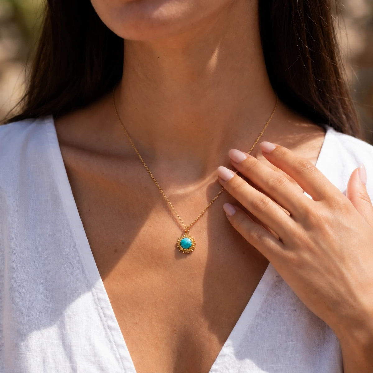 Round turquoise pendant necklace worn with a white blouse.