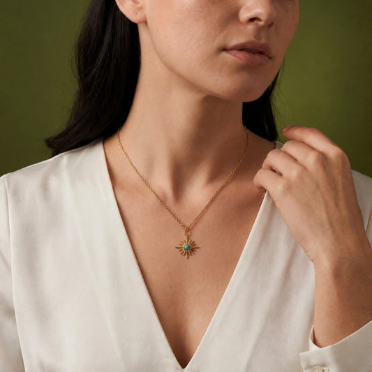 Starburst turquoise pendant necklace worn with a white blouse.