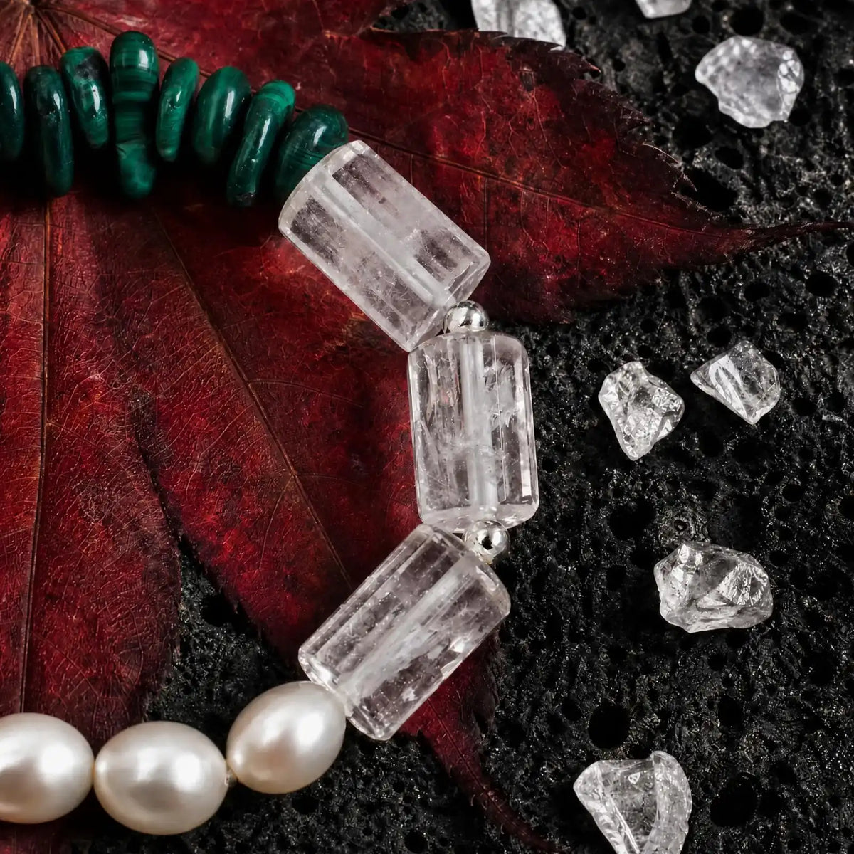Styled display of the Verdant Circuit Malachite & Onyx Bracelet showing green malachite, black onyx, clear quartz, pearl, and spotted stone sections