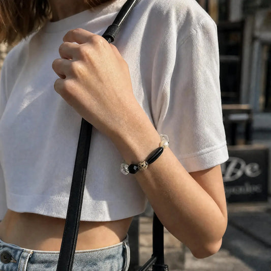 Styled wrist view of the Speckled Moon Mixed-Stone Bracelet with black, pale, clear, pearl, and speckled natural stone forms