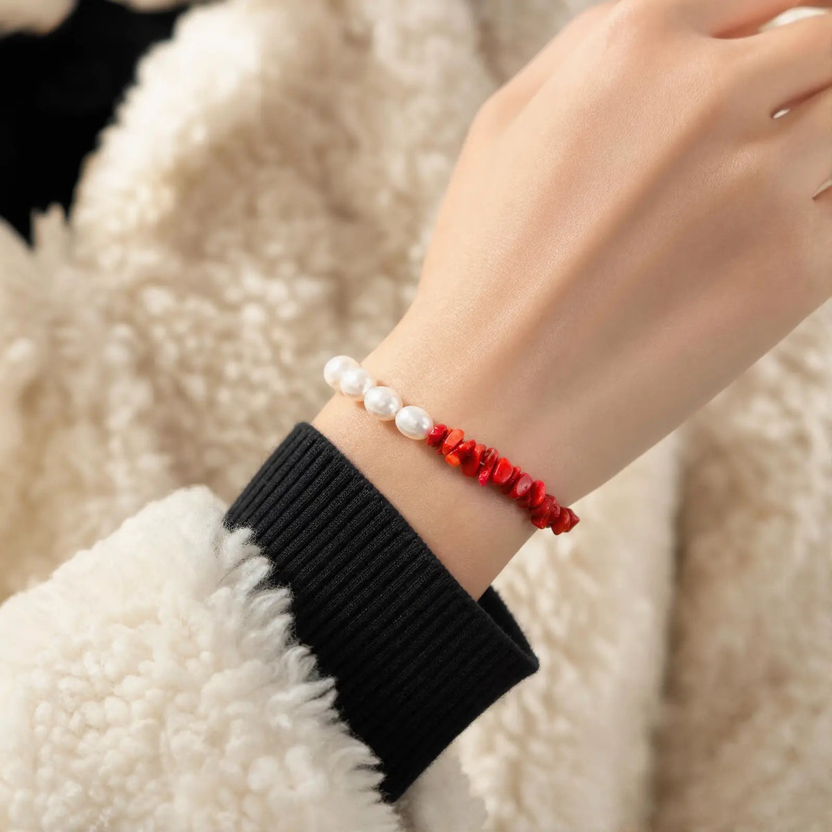 Wrist view of the Crimson Divide Pearl Bracelet with an asymmetric split of red stone chips and freshwater pearls