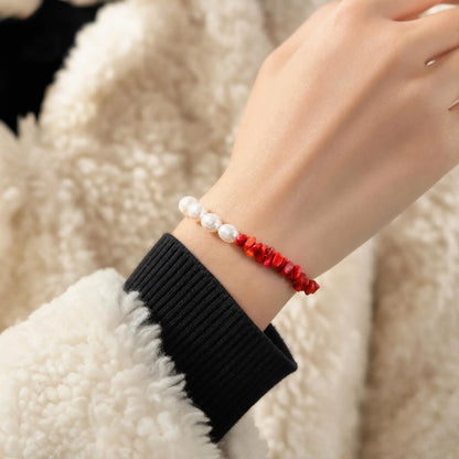Wrist view of the Crimson Divide Pearl Bracelet with an asymmetric split of red stone chips and freshwater pearls